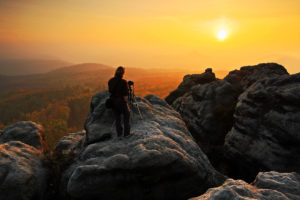 Videographer on to of a mountain at sunset